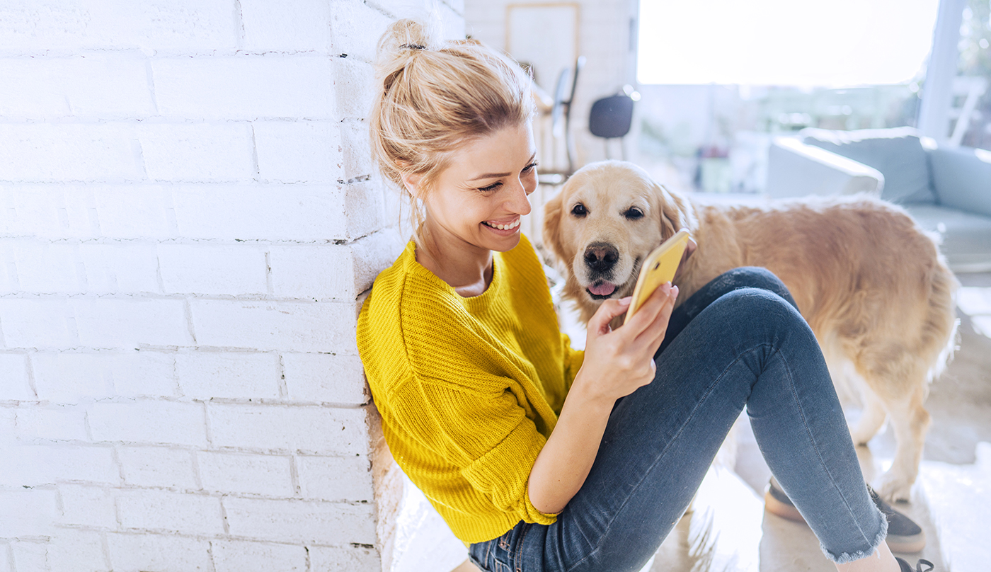 woman sitting against wall with her dog wearing yellow sweater 