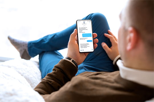 Man in brown shirt reading texts on his phone